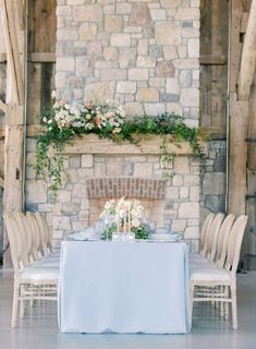 the table is set with white flowers and candles on it, along with other chairs