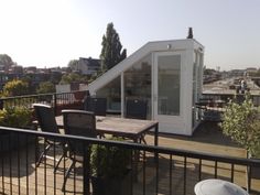 a small white building sitting on top of a roof next to a table and chairs