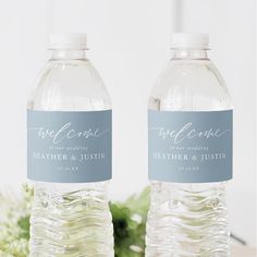 two bottled water bottles sitting next to each other on a table with flowers in the background