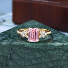 a pink tourmaline and diamond ring sitting on top of a green marble slab