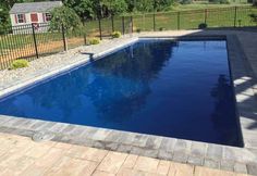 an empty swimming pool in the middle of a yard with fenced in area around it