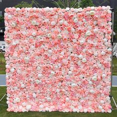 a large pink and white flowered wall in the grass