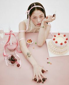 a woman sitting at a table with a cake and candy in front of her face