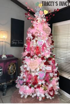 a pink and white christmas tree decorated with hearts