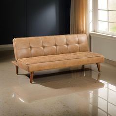 a tan leather couch sitting in front of a window