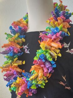 a woman wearing a colorful necklace made out of candy bars and candies on her neck