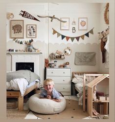 a little boy that is laying down on a bed in a room with many pictures