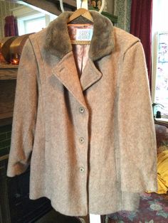 Made by Surrey Classics, this coat is made of a wool and rayon blend in a sandy light brown or taupey colour. It has original buttons, two outer pockets, a detail on the shoulders and it is fully lined. In excellent condition. The measurements, taken with the coat lying flat, are: shoulder to shoulder, 19 inches; armpit to armpit, 24 inches; sleeves, 24 inches; bottom edge, 25 inches; total length, 35 inches. Classic Beige Outerwear With Faux Fur Lining, Classic Fitted Wool Coat, Classic Long Wool Fur Coat, Fitted Wool Fur Coat For Fall, Classic Mink Outerwear With Faux Fur Lining, Classic Mink Outerwear For Winter, Classic Beige Fur Coat For Workwear, Classic Fitted Wool Fur Coat, Beige Wool Fur Coat For Winter