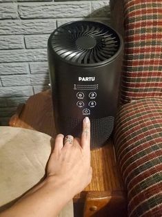 a person pointing at a portable air conditioner on a table next to a couch