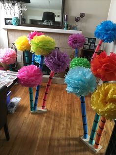 colorful paper pom poms are lined up on the floor in front of a fireplace