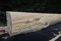 a large piece of wood sitting on top of a black rug in front of trees