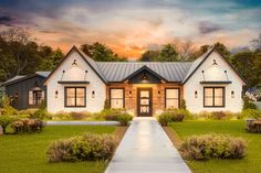 a white house with black trim and windows on the front lawn at sunset or dawn