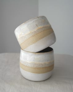 two white bowls sitting on top of a table next to each other with brown stripes