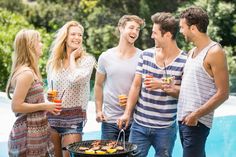 a group of people standing next to each other near a pool with drinks in their hands