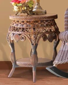 a wicker side table with flowers on top and a rocking chair next to it