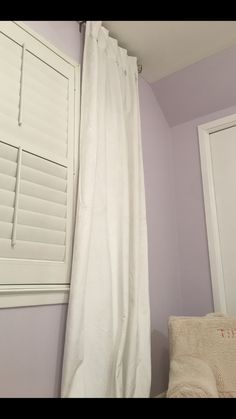 there is a white curtain hanging in the corner of this room with purple walls and flooring