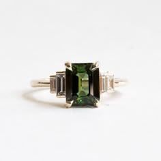 an emerald and diamond ring with three baguets