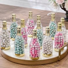 there are many small bottles with candy in them on the tray next to some flowers