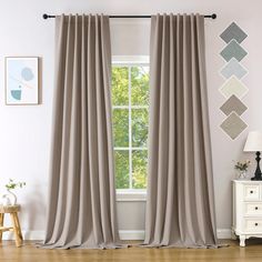 a living room with white walls and wooden floors, two windows covered in gray curtains