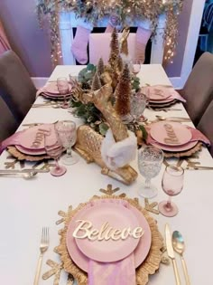 the table is set with pink and gold plates, silverware, and napkins