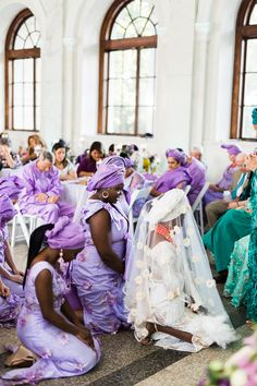 a group of people sitting around each other in purple dresses and veils on their heads