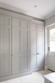 an empty room with white cupboards and drawers on the wall, in front of a window