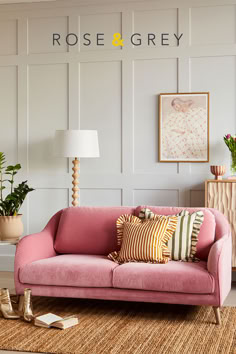 a living room with pink couches and potted plants on the side table next to it