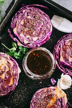 three red cabbages sitting on top of a pan next to a bowl of dressing