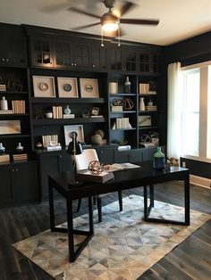 a home office with black bookcases and wooden flooring is pictured in this image