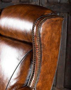 a brown leather reclining chair with studding on the arm and backrests