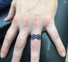 a person's hand with a small tattoo on the middle finger and an arrow in the middle