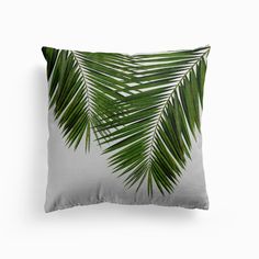 a white pillow with green palm leaves on it