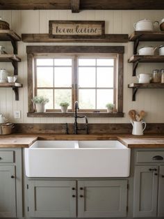 a white kitchen sink sitting under a window next to open shelving units and wooden shelves