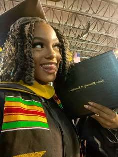 a woman in a graduation cap and gown holding up a book with writing on it