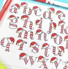 the letters are decorated with santa hats and striped stockings on white paper next to markers