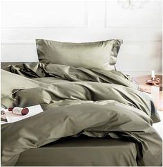 an unmade bed with green sheets and pillows