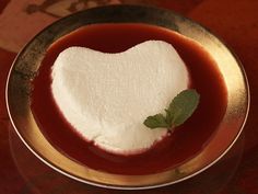 a heart shaped piece of sugar sitting in a bowl filled with red liquid on top of a wooden table