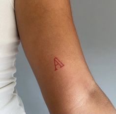 a woman's arm with a small red tattoo on the left side of her arm