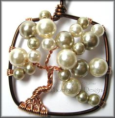 a wire wrapped necklace with white pearls and copper beads on it's end, in the shape of a tree ornament