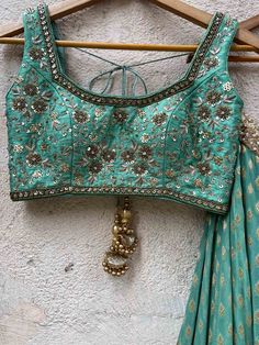 A three-piece jade green zari lehenga set from the Priti Sahni collection. This beautiful georgette small butti green lehenga with a heavy border of sequin, pearl and zari work detail with green accent is paired with a raw silk green blouse with sequin and zardosi embroidery detail all over. The lehenga has side hanging ball tassels to the waistline. And the blouse has a sequins tassel tie-up at the back. This outfit is completed with a sequin tulle dupatta with jade green accent in net material Green Embellished Semi-stitched Anarkali Set, Bollywood Style Embellished Green Anarkali Set, Embellished Green Georgette Anarkali Set, Green Embellished Sets For Navratri, Festive Green Embellished Sharara, Festive Embellished Green Sharara, Green Embellished Anarkali Choli, Anarkali Embellished Green Choli, Green Embellished Designer Traditional Wear