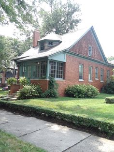 a red brick house sitting on top of a lush green field