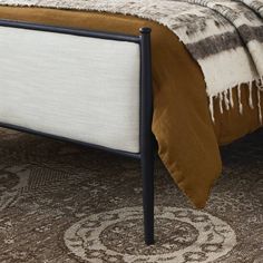 a bed with a brown and white comforter on it's headboard next to a rug