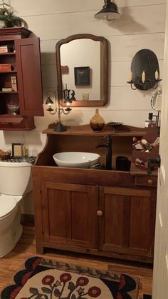 a bathroom with a sink, toilet and wooden cabinet in the corner on the floor