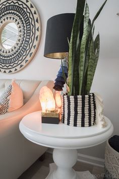 a white table topped with a lamp and a potted plant next to a mirror