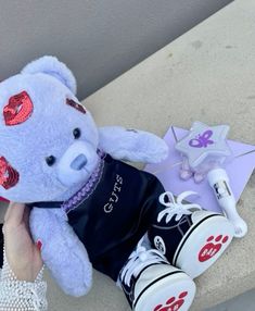 a white teddy bear sitting on top of a counter next to a pair of shoes