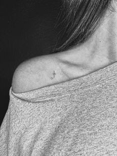 a woman's neck with a small cross tattoo on the left side of her neck