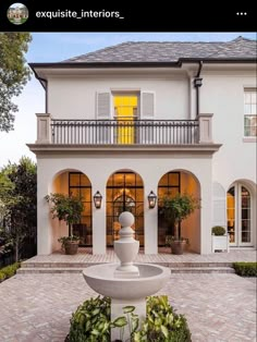 a large white house with a fountain in the front yard