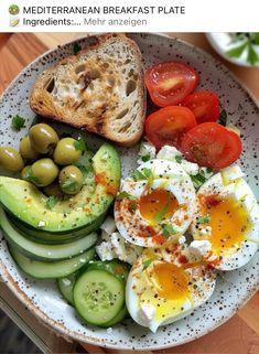 a white plate topped with an egg, cucumber and tomato slices next to bread