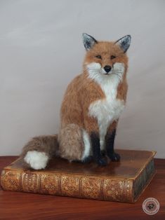 a stuffed fox sitting on top of a book