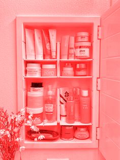 an open medicine cabinet filled with lots of different types of beauty products and flowers in a vase